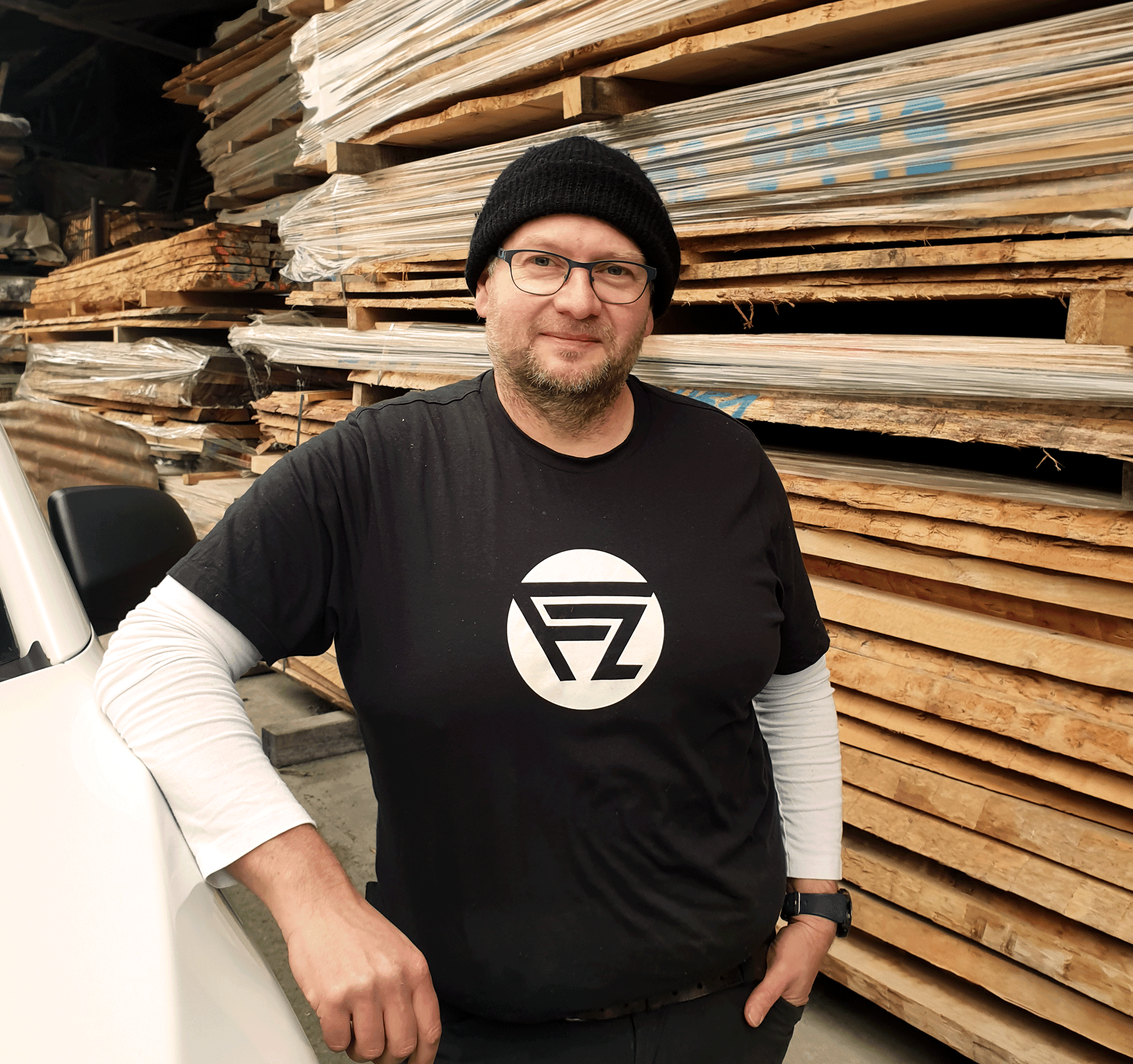 Frank_Zenth_Bunt Schreinermeister Zenth im Holzlager vor gestapeltem Bauholz - Profilbild für Unternehmenswebsite