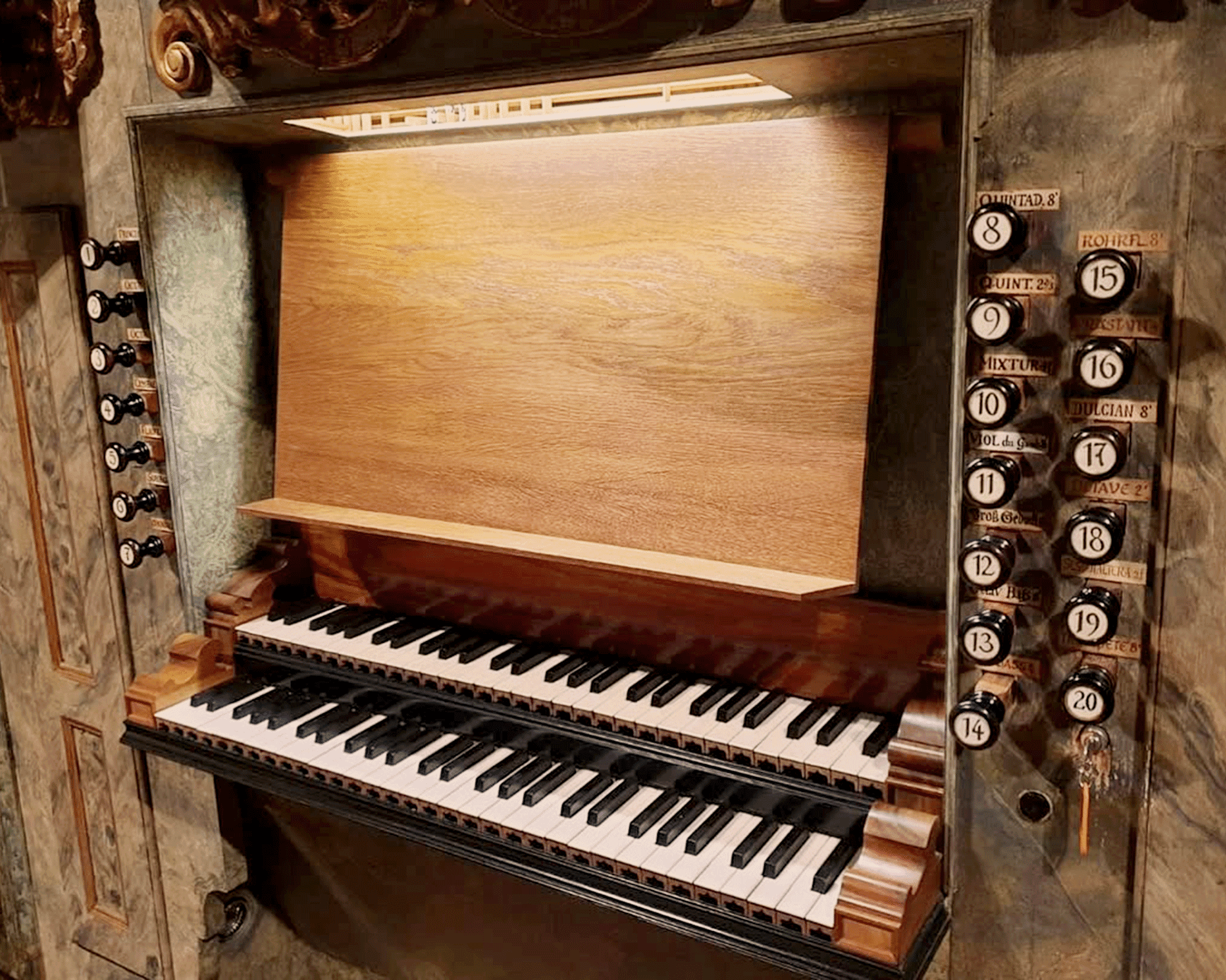Manuale und Registerzüge einer historischen Kirchenorgel mit hölzernem Spieltisch und barocken Verzierungen.